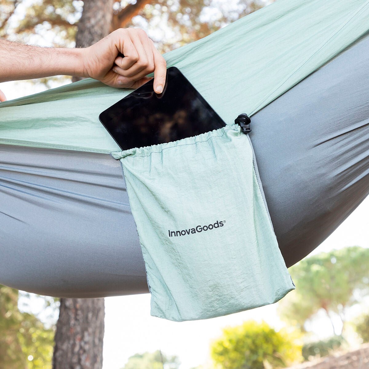 Close-up of a built-in hammock storage pocket holding a tablet, showing convenient access to essentials while lounging.